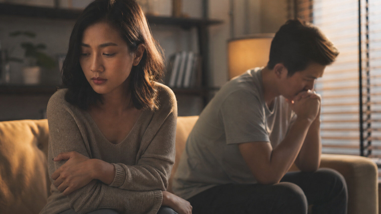 Pasangan duduk tenang di ruang tamu, tampak lelah secara emosional sambil merenungkan hubungan toxic dan dampaknya pada kesehatan mental